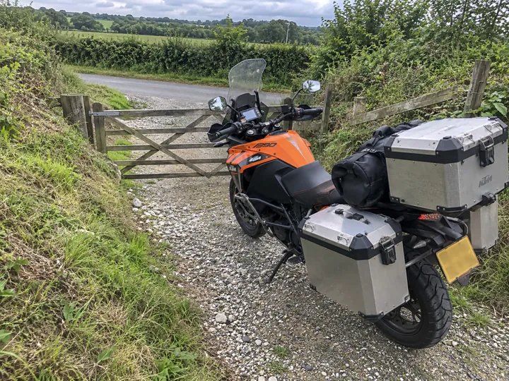A loaded KTM parked nose-down toward a closed farm gate